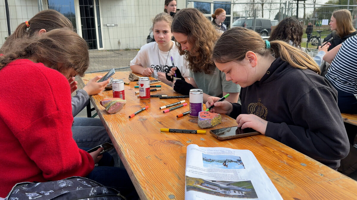 Leerlingen tijdens het versieren van stenen voor hart campus Terneuzen.jpg